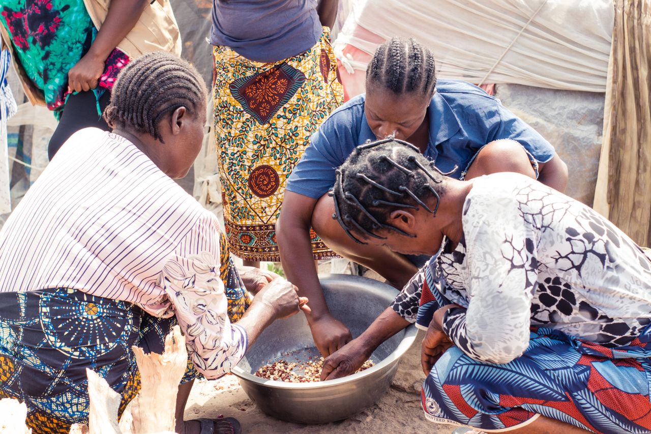 Home Group of women collaboratively sorting beans outdoors, showcasing cultural richness.